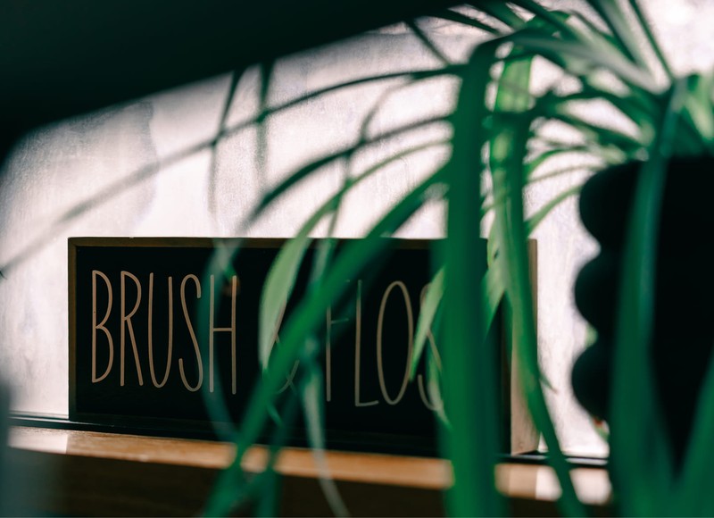 a woman looking herself in a handheld mirror sitting in a dental office